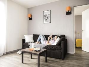 a woman laying on a couch in a living room at Aparthotel Adagio Access Orléans in Orléans