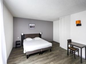 a bedroom with a bed and a table and a desk at Aparthotel Adagio Access Orléans in Orléans +52 photos