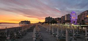 a beach with chairs and a ferris wheel at sunset at TinaToni Apartment in Follonica