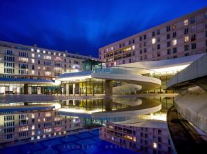 a building with a reflection in the water at night at Studio cosy proche plage & centre in Le Havre