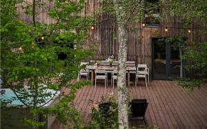 a patio with a table and chairs and a tree at La Râu 663A - Riverside Mountain Chalet with Outdoor Jacuzzi in Porumbacu de Sus