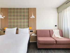 a hotel room with a bed and a couch at ibis Styles Annecy Centre Gare in Annecy +70 photos