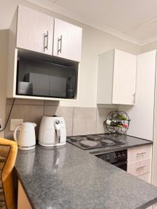 a kitchen with white cabinets and a stove top oven at Kilimanjaro in Alberton +12 photos