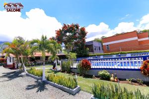 a garden with palm trees and a blue fence at Complejo Campestre Salome Cabañas & Hotel in Calima +9 photos