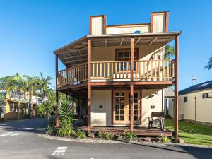 a large house with a balcony on a street at Wairo Beach Holiday Park in Lake Tabourie