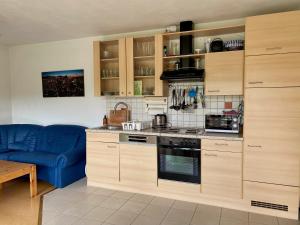 a kitchen with wooden cabinets and a blue couch at Apartment with Terrace & Garden View in Zwiesel +7 photos