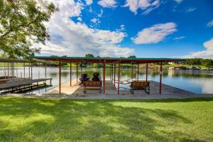 two people sitting on benches under a pavilion next to a lake at Renovated Waterfront Home with WiFi, Lake Views, Dock & Boat Lift - Dogs OK in Buchanan Dam