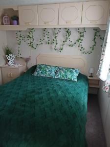 a bedroom with a bed with a green comforter at Chatka in Nasutów