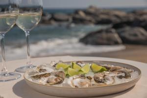 a plate of oysters with lime slices and wine glasses at Hotel Mae in Maitencillo +113 photos