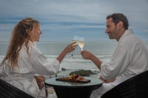 a man and woman holding glasses of wine on the beach at Hotel Mae in Maitencillo