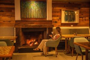 a woman sitting in front of a fireplace in a restaurant at Hotel Mae in Maitencillo