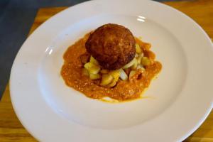 a white plate with a meatball on top of food at AsiaTica Lodge Volcano and Lake View in El Castillo de La Fortuna +9 photos