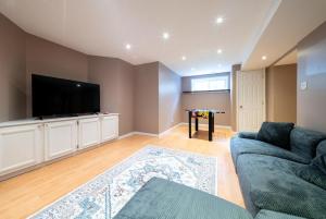 a living room with a couch and a flat screen tv at Pool, BBQ & Foosball Spacious 4BR Home in Gatineau