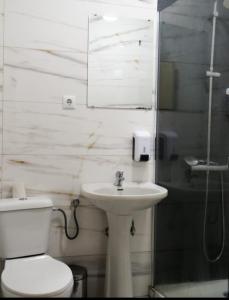 a white bathroom with a toilet and a sink at Residencial Moderna in Figueira da Foz
