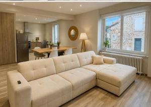 a living room with a white couch and a kitchen at Maison de vacances in Capdenac-Gare