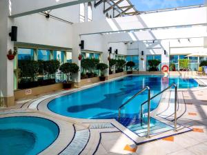a large swimming pool in a building with a hotel at Grand Mercure Majlis Residences Abu Dhabi in Abu Dhabi