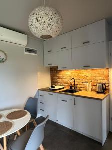 a kitchen with white cabinets and a table and chairs at Twoje Rydzewo in Rydzewo