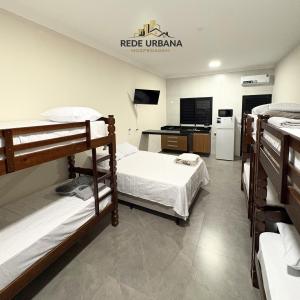 a room with three bunk beds and a kitchen at Loft 7 com ar-condicionado da Rede Urbana in Indaiatuba