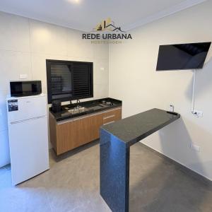 a kitchen with a white refrigerator and a counter with a tv at Loft 9 com ar-condicionado da Rede Urbana in Indaiatuba