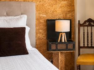 a bedroom with a bed and a lamp in a suitcase at Casa do Criativo ® Bed&Breakfast in Almada