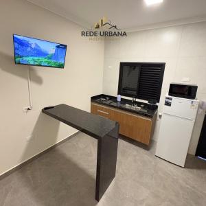 a room with a table and a tv on a wall at Loft 10 com ar-condicionado da Rede Urbana in Indaiatuba