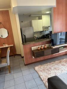 a living room with a large television and a kitchen at Apartamento, Campos dos Goytacazes, centro in Campos dos Goytacazes