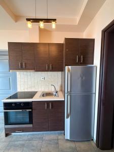 a kitchen with a stainless steel refrigerator and wooden cabinets at Gonis Suites in Palaiochora