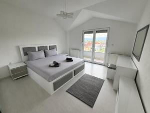 a white bedroom with a large bed and a window at Serenity Apartment in Struga