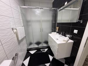 a black and white bathroom with a shower and a sink at Serenity Apartment in Struga +15 photos