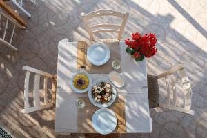 a table with plates of food and a vase of flowers at Mesogios Beach in Kissamos