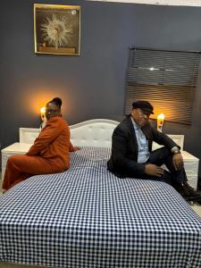 two men sitting on top of a bed at Qten Camp in Pietermaritzburg