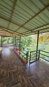 a pavilion with a wooden floor and a view of the water at Adan Paradise Riverview Homestay in Attappādi