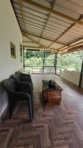 a living room with black chairs and a coffee table at Adan Paradise Riverview Homestay in Attappādi +9 photos