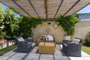 a patio with wicker chairs and a couch under a pergola at Olympe de Provence in Caromb