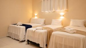a room with three beds with white sheets at Nura Pousada in Maragogi