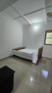 a bedroom with a bed in a white room at Adan Paradise Riverview Homestay in Attappādi
