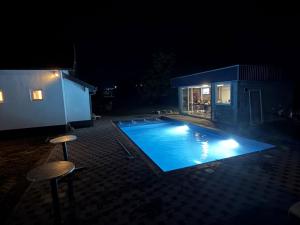 a swimming pool at night with two stools around it at Vikend Kuca Okanovic in Gradačac