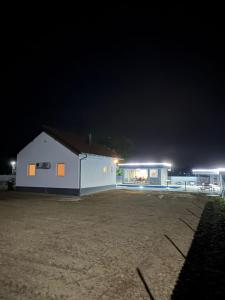 a white building with lights in a parking lot at night at Vikend Kuca Okanovic in Gradačac