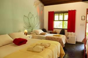 a bedroom with two beds with red curtains at Pousada Rancho da Serra PETAR in Iporanga