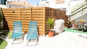 two blue chairs sitting in front of a wooden fence at Casinha Alice in Nazaré
