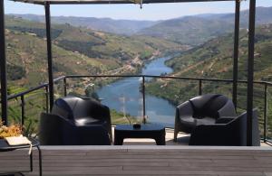 two chairs and a table on a balcony overlooking a river at Casa Vale do Douro in Mesão Frio