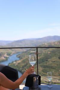 a woman holding a glass of wine on a table at Casa Vale do Douro in Mesão Frio