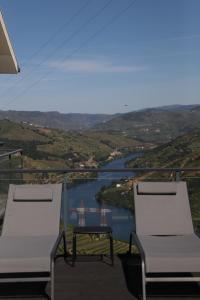 two chairs and a table on a balcony overlooking a river at Casa Vale do Douro in Mesão Frio