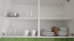a white cabinet filled with plates and cups and dishes at Apartamentos en playa Canido in Malpica