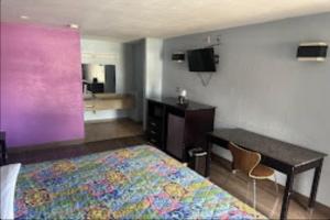 a hotel room with a bed and a desk and a bed and a table at Relax Inn Hotel in Birmingham