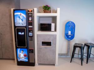 a video game vending machine next to a microwave at ibis budget Haguenau Strasbourg Nord in Haguenau
