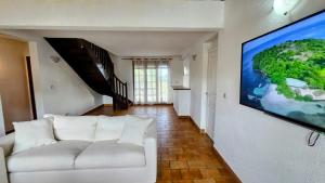 a living room with a white couch and a flat screen tv at Les 2 Cocotiers - Maison d'hôtes d'Eugénie in Sainte-Luce