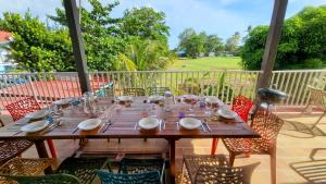 a wooden table with plates and glasses on a patio at Les 2 Cocotiers - Maison d'hôtes d'Eugénie in Sainte-Luce