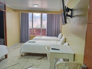 a room with two beds and a table and a window at Hotel ROYALS HUARAZ in Huaraz
