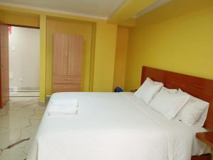 a bedroom with a large white bed with yellow walls at Hotel ROYALS HUARAZ in Huaraz